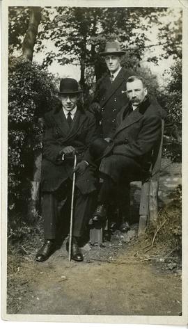 3 men in suits; on verso: "Roy sitting down, Eric standing"