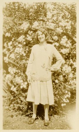 Marjorie Martin standing in front of flower bush